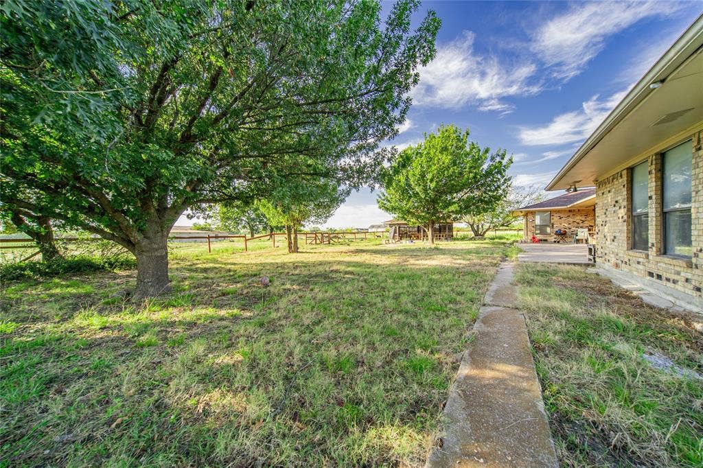 4320 Hickox Road, Rowlett, TX 75089 Expansive grassy area with mature trees and a concrete pathway leading to a covered patio
