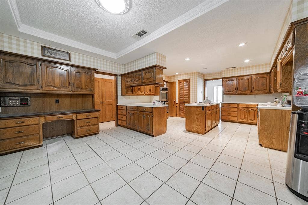 4320 Hickox Road, Rowlett, TX 75089 Kitchen featuring extensive wood cabinetry, white tile flooring, built-in desk area, and a central island