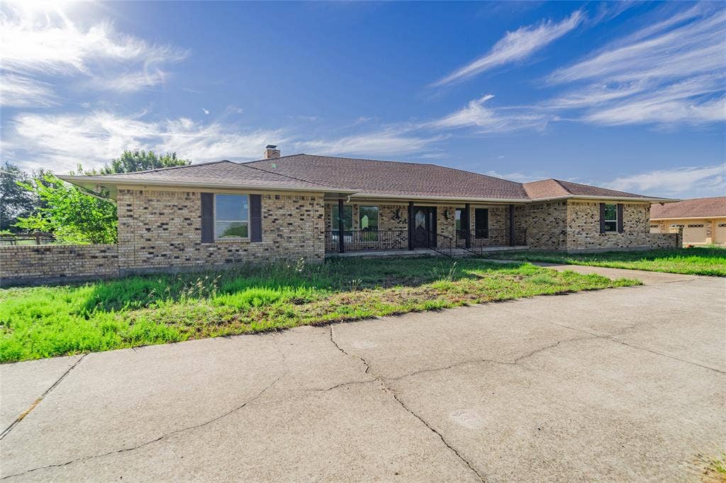 4320 Hickox Road, Rowlett, TX 75089 Brick exterior with brown shingle roofing, featuring a covered front entry and a concrete driveway