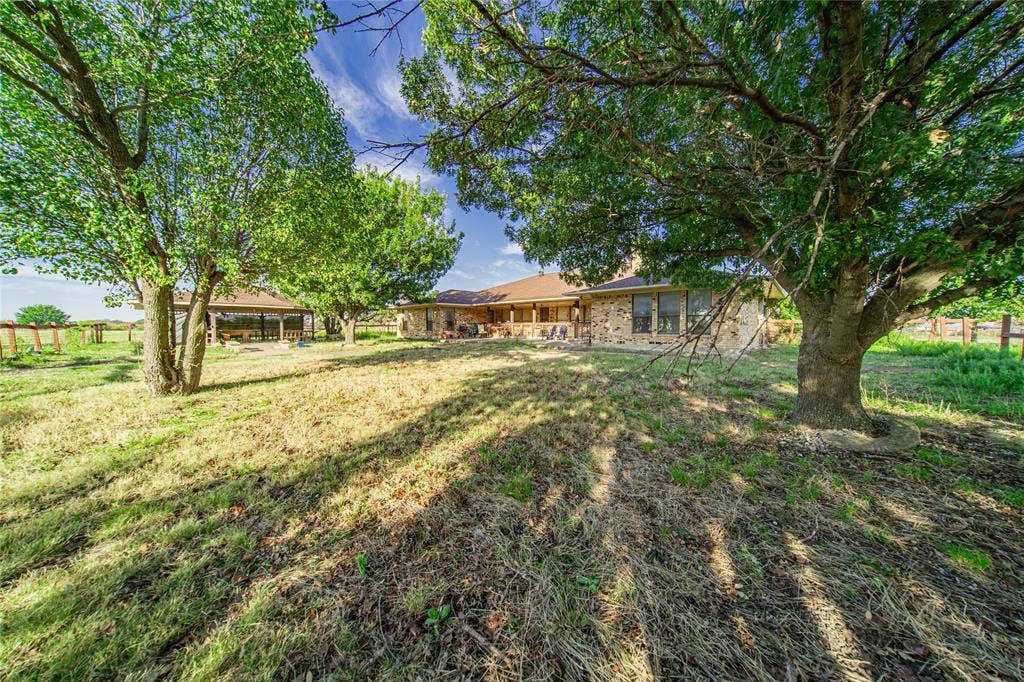 4320 Hickox Road, Rowlett, TX 75089 Stone exterior featuring multiple windows and a covered patio