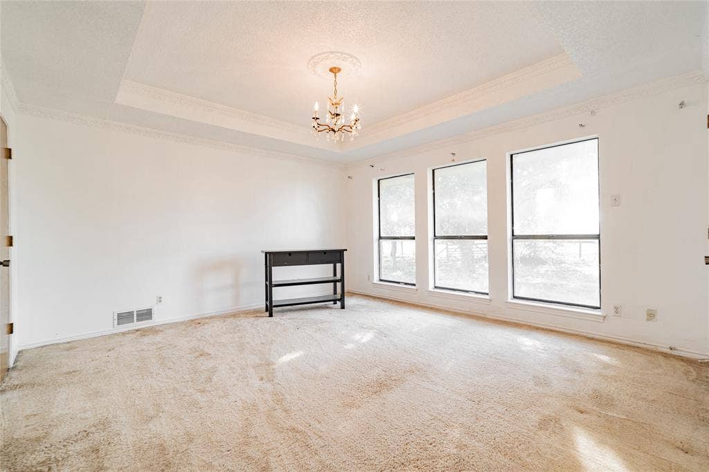 4320 Hickox Road, Rowlett, TX 75089 Tray ceiling with crown molding, decorative chandelier, and three large windows