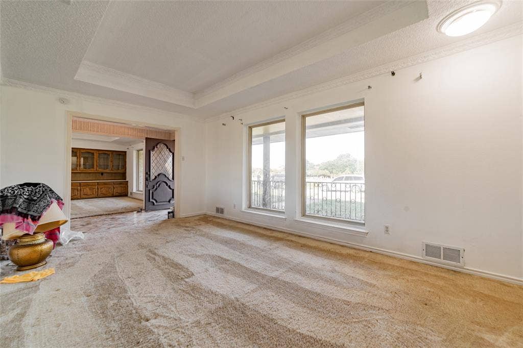 4320 Hickox Road, Rowlett, TX 75089 Tray ceiling with crown molding, dual large windows, and an arched doorway leading to an additional space featuring built-in cabinetry