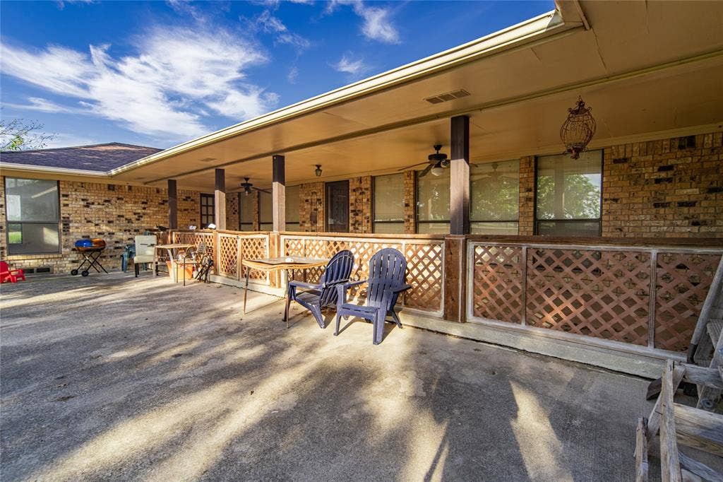 4320 Hickox Road, Rowlett, TX 75089 Expansive concrete patio with a covered porch featuring ceiling fans, lattice detailing, and exterior lighting