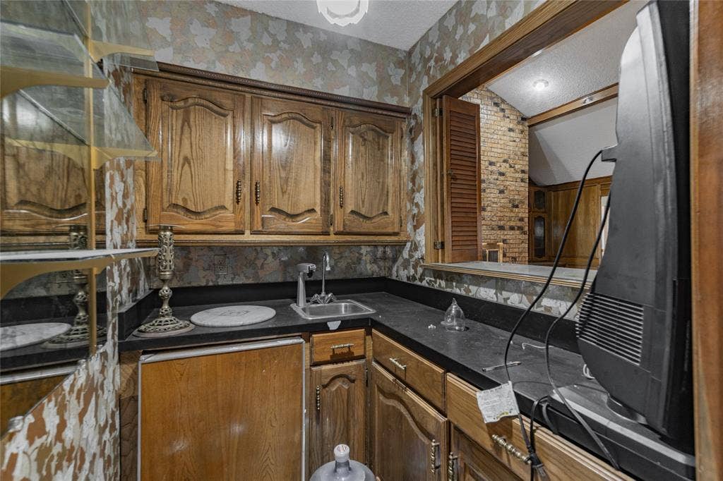 4320 Hickox Road, Rowlett, TX 75089 Wood cabinetry with black countertops, integrated sink, and pass-through window