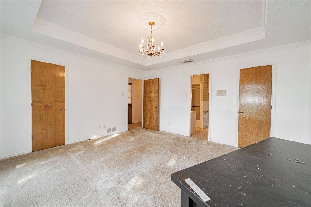 4320 Hickox Road, Rowlett, TX 75089 Tray ceiling with decorative molding, chandelier lighting, white walls, and wood-panel doors