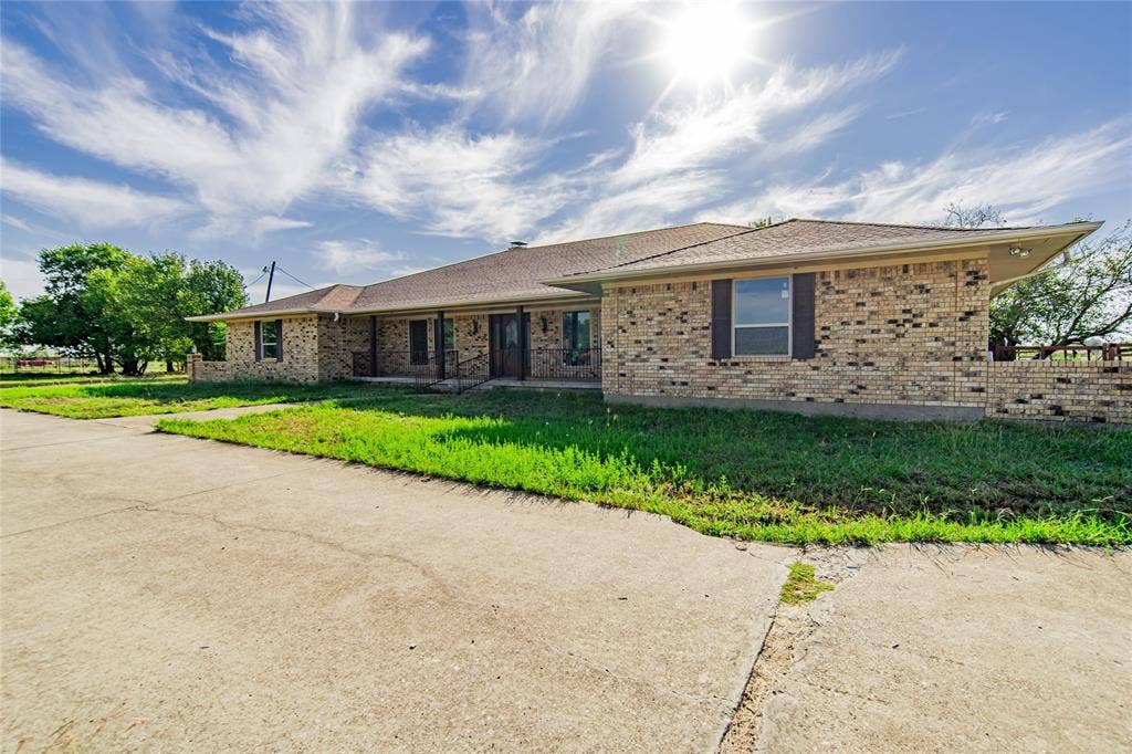 4320 Hickox Road, Rowlett, TX 75089 Brick exterior with brown roof shingles, covered porch entry, and dark window shutters