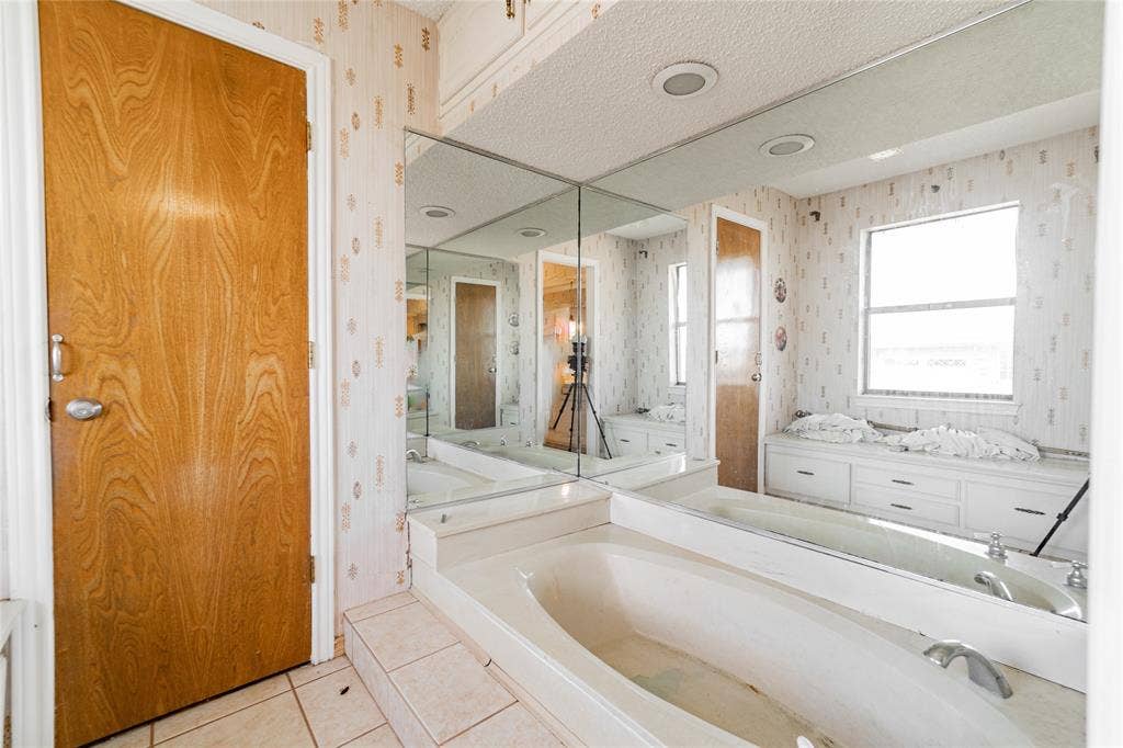 4320 Hickox Road, Rowlett, TX 75089 Built-in bathtub with tiled surround, mirrored wall, window with storage bench, and recessed lighting