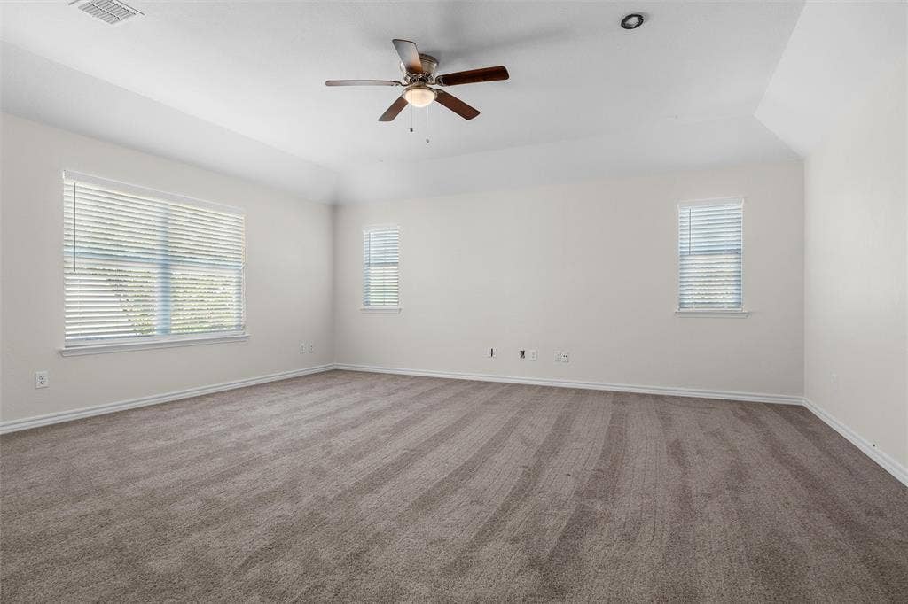 Expansive room featuring vaulted ceilings, a ceiling fan with integrated lighting, recessed lighting, two windows with blinds, and neutral carpeting