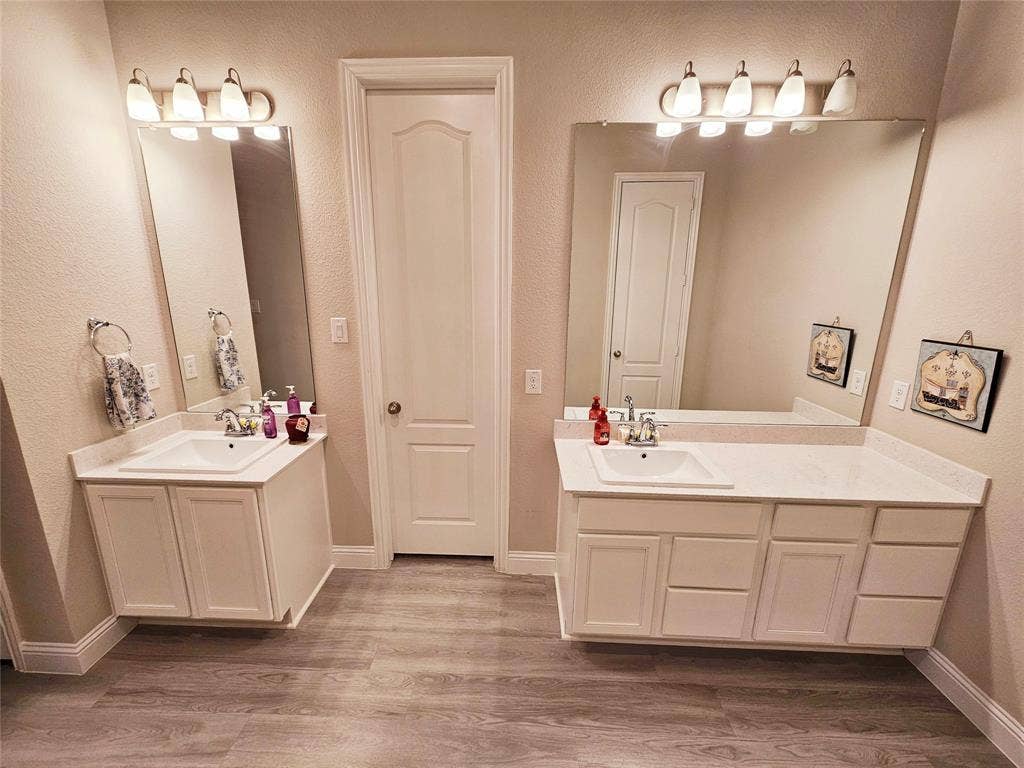 Dual vanity sinks with white cabinetry, integrated countertops, and individual mirrors