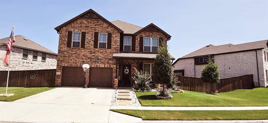 Brick exterior with dark shutters, covered front entry, and a two-car garage