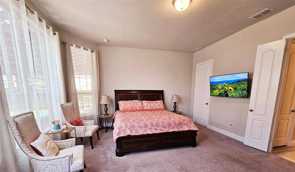 Spacious room featuring carpeted flooring, multiple windows, a ceiling-mounted light fixture, and two white panel doors