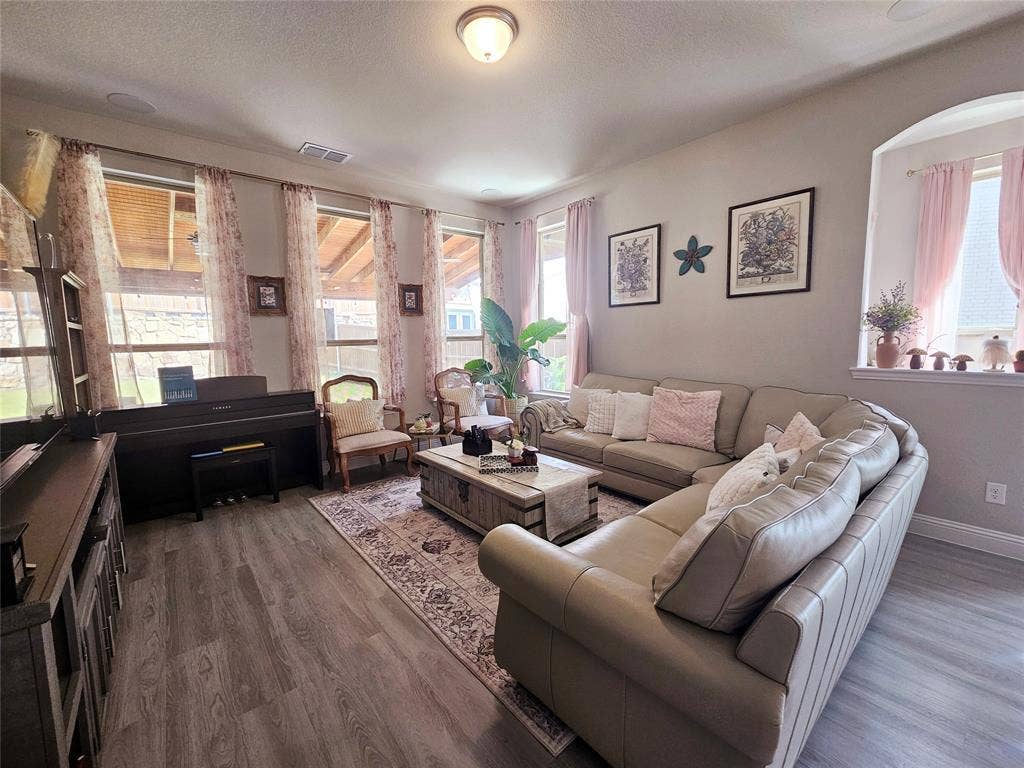 Wood-finish flooring throughout, multiple large windows, and an arched window alcove