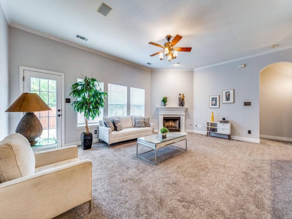 5604 Parkplace Drive, Denton, TX 76226 Spacious living area featuring high ceilings, crown molding, a built-in fireplace, multiple windows with blinds, and an arched entry