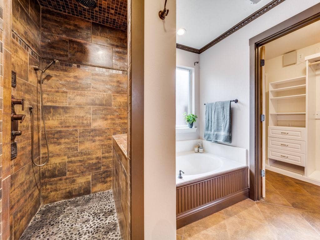 5604 Parkplace Drive, Denton, TX 76226 Walk-in shower with natural stone tile and pebble-stone flooring, featuring a built-in bench and a rain showerhead