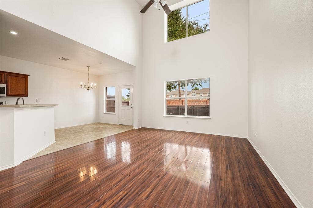 4535 Woodsboro Lane, Plano, TX 75024 Soaring ceilings with a high-mounted window, wood-finish flooring, a contemporary ceiling fan, and an open-concept layout to the dining area featuring a chandelier