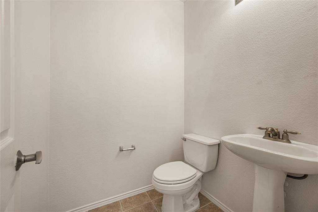4535 Woodsboro Lane, Plano, TX 75024 Pedestal sink with a two-handle faucet, white toilet, and tiled flooring