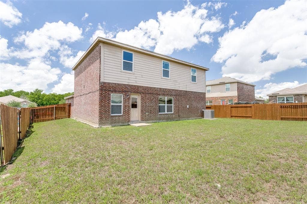Expansive fenced backyard with a two-story brick and siding exterior