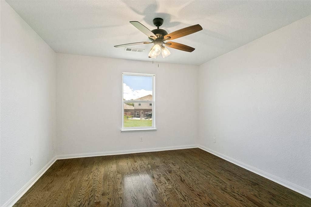 Room featuring dark wood-finish flooring, white walls, and a ceiling fan with integrated lighting