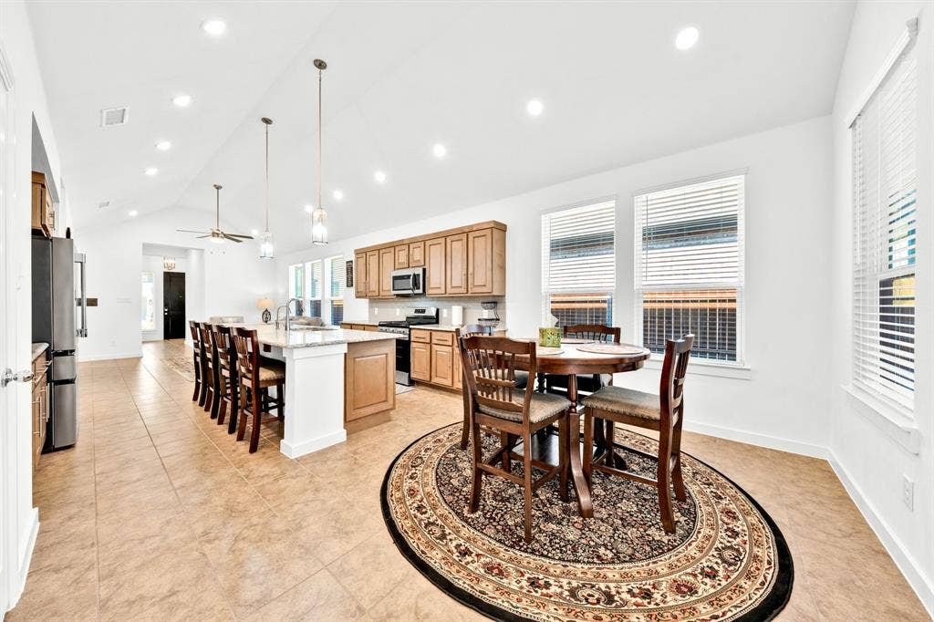 3928 Bison Lane, Crandall, TX 75114 Vaulted ceiling kitchen featuring recessed lighting, a center island with bar seating, wood cabinetry, and tile flooring