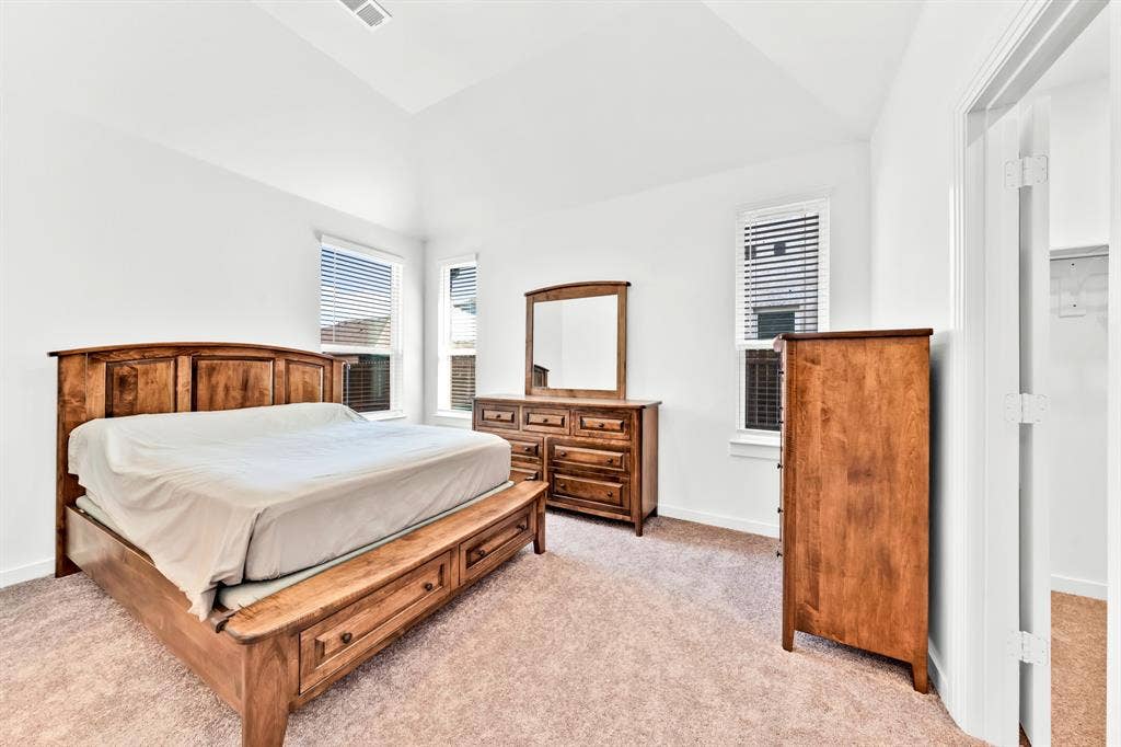3928 Bison Lane, Crandall, TX 75114 Vaulted ceiling, two windows with blinds, light-toned carpeting, and white walls