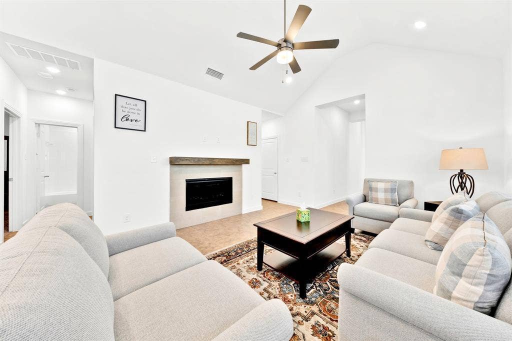 3928 Bison Lane, Crandall, TX 75114 Vaulted ceiling with an integrated ceiling fan, fireplace with a wood mantel, tile flooring, recessed lighting, and a white interior