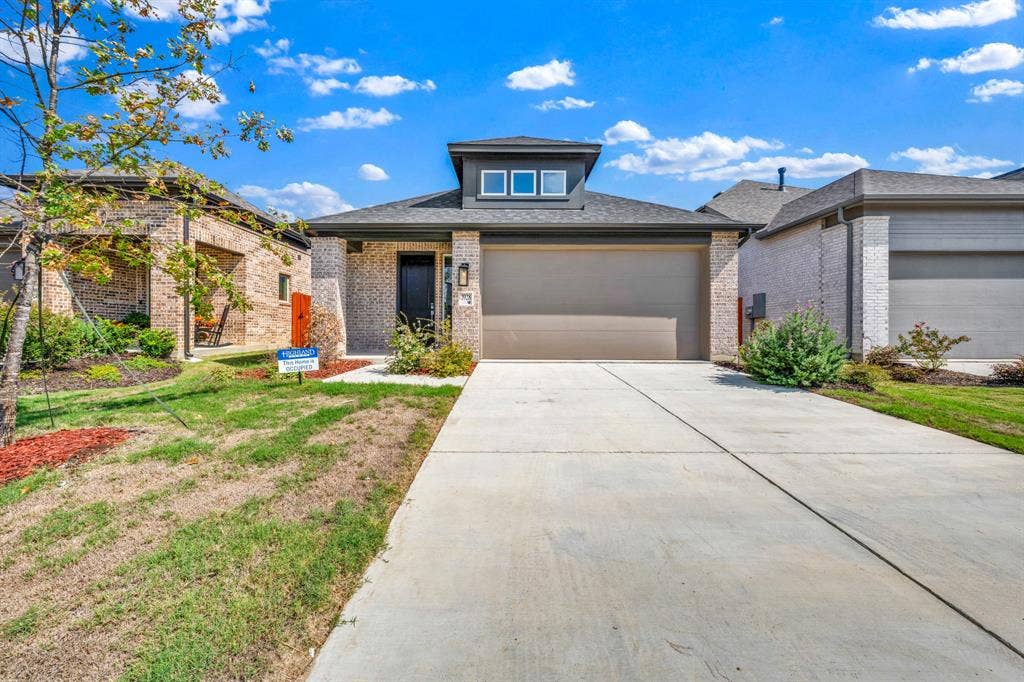 3928 Bison Lane, Crandall, TX 75114 Brick facade with a contrasting dark front door, attached garage, and concrete driveway