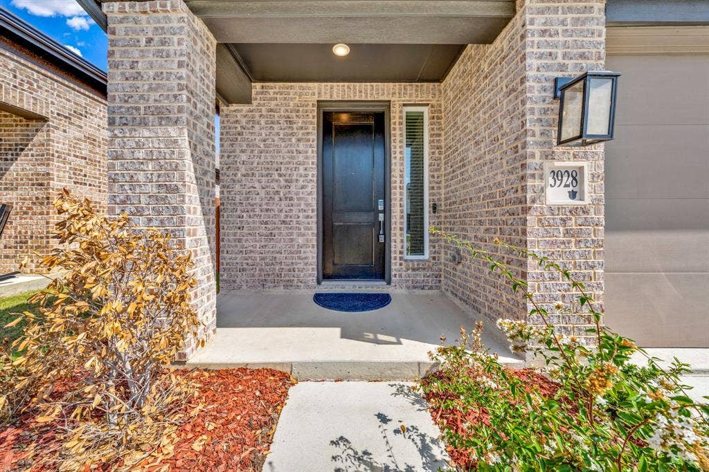 3928 Bison Lane, Crandall, TX 75114 Brick facade with dark trim, covered porch, and a dark front entry door