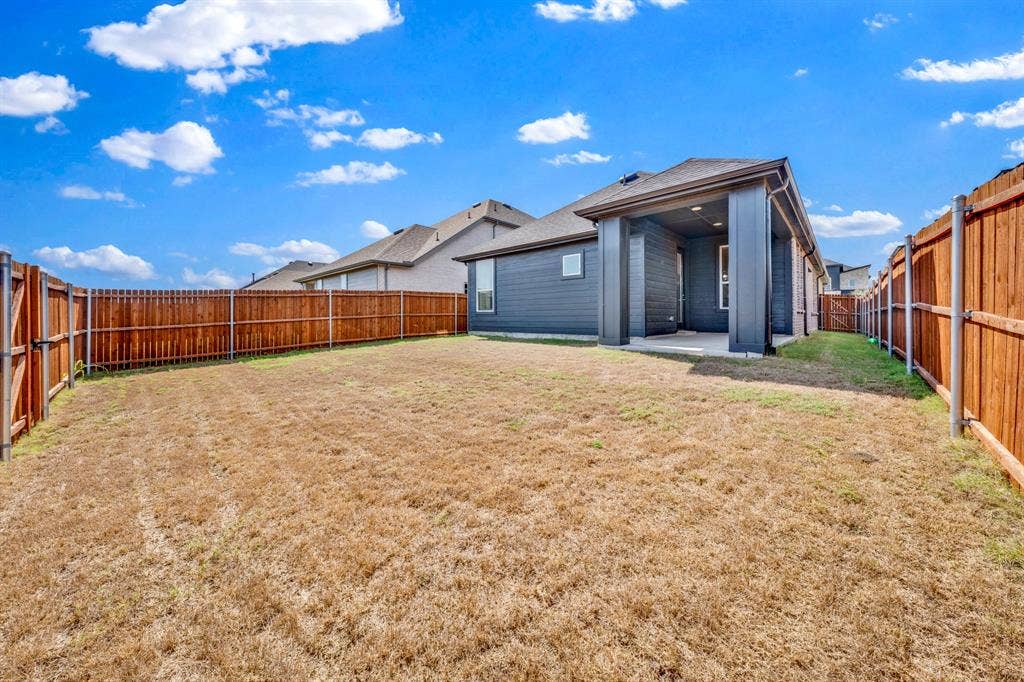 3928 Bison Lane, Crandall, TX 75114 Expansive backyard with wood fencing and a covered patio