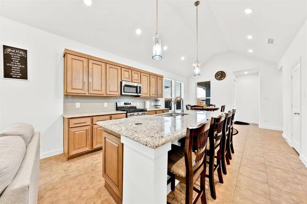 3928 Bison Lane, Crandall, TX 75114 Kitchen featuring light wood cabinetry, a large center island with a light-toned countertop, stainless steel appliances, and recessed lighting