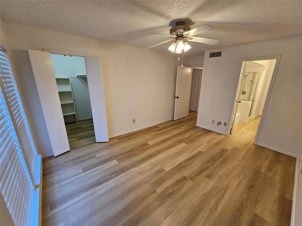 Primary bedroom featuring ensuite bathroom, spacious closet & ceiling fan