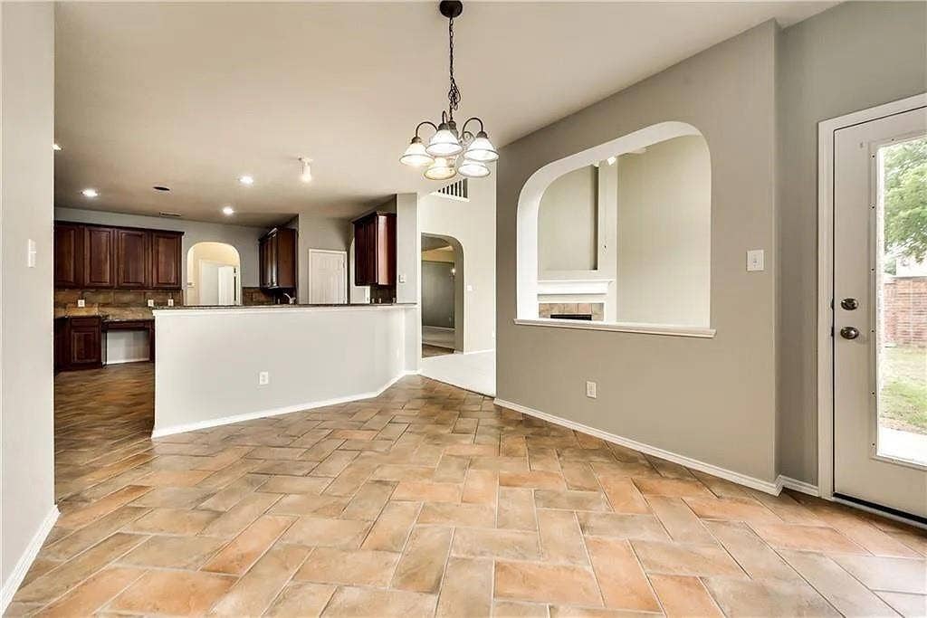 9304 Regal Oaks Drive, McKinney, TX 75072 Herringbone pattern tile flooring, arched wall cut-out, built-in cabinetry, breakfast bar, and pendant lighting