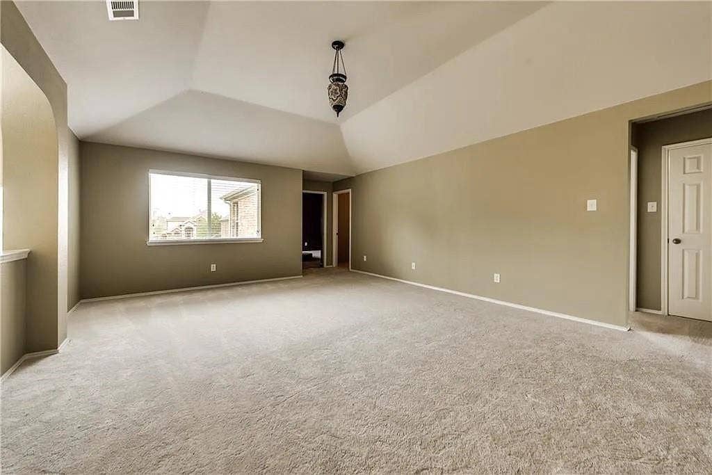 9304 Regal Oaks Drive, McKinney, TX 75072 Vaulted ceiling with an ornate pendant light fixture, soft carpet flooring, and a large window
