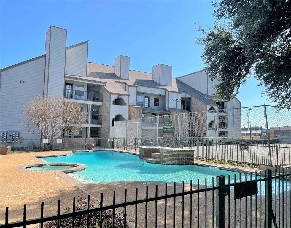 6108 Abrams Road, #118, Dallas, TX 75231 Community swimming pool with an integrated spa, surrounded by a black metal fence and concrete decking