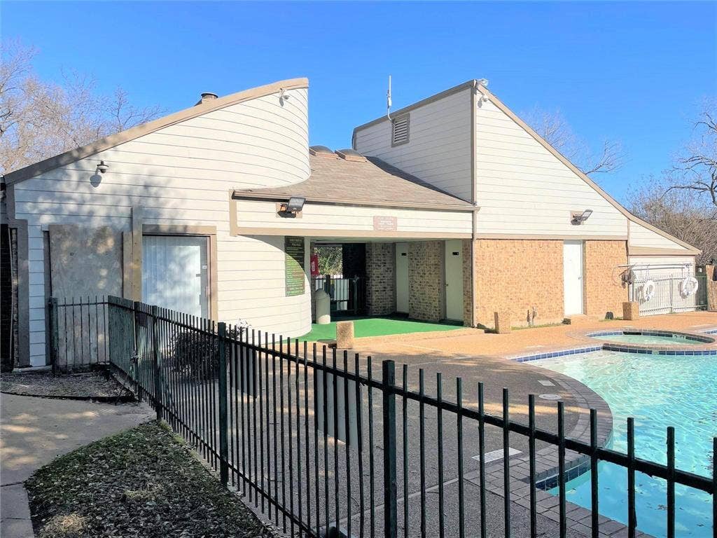 6108 Abrams Road, #118, Dallas, TX 75231 Swimming pool with integrated spa, black metal perimeter fencing, and a surrounding paved deck