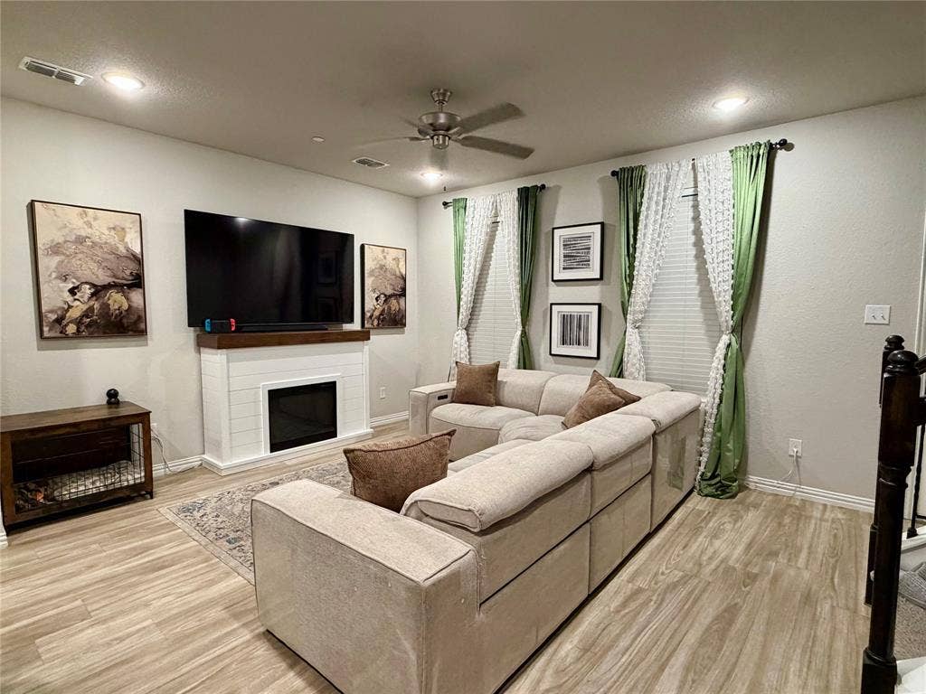 2812 Appaloosa Lane, Mesquite, TX 75150 Recessed lighting, wood-finish flooring, ceiling fan, shiplap-detailed fireplace, and multiple windows with blinds