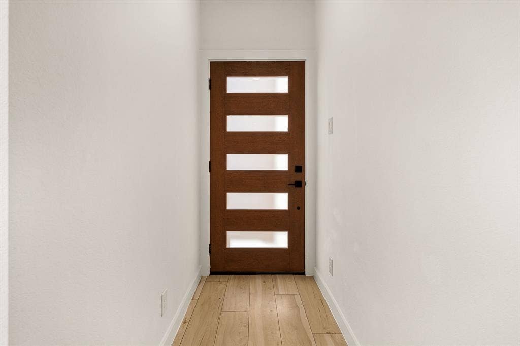 2232 Hooper Street, Dallas, TX 75215 Wood-finish flooring, modern door with frosted glass panels, matte black hardware, and light-colored walls