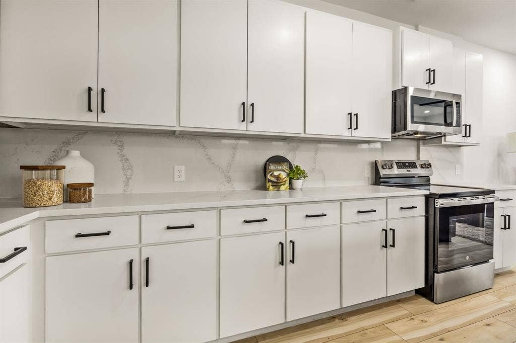 2232 Hooper Street, Dallas, TX 75215 White cabinetry with matte black hardware, quartz countertops, full-height backsplash, and stainless steel appliances