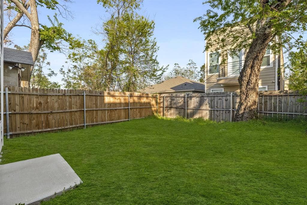 2232 Hooper Street, Dallas, TX 75215 Expansive backyard featuring a manicured lawn, wood fencing, and mature trees