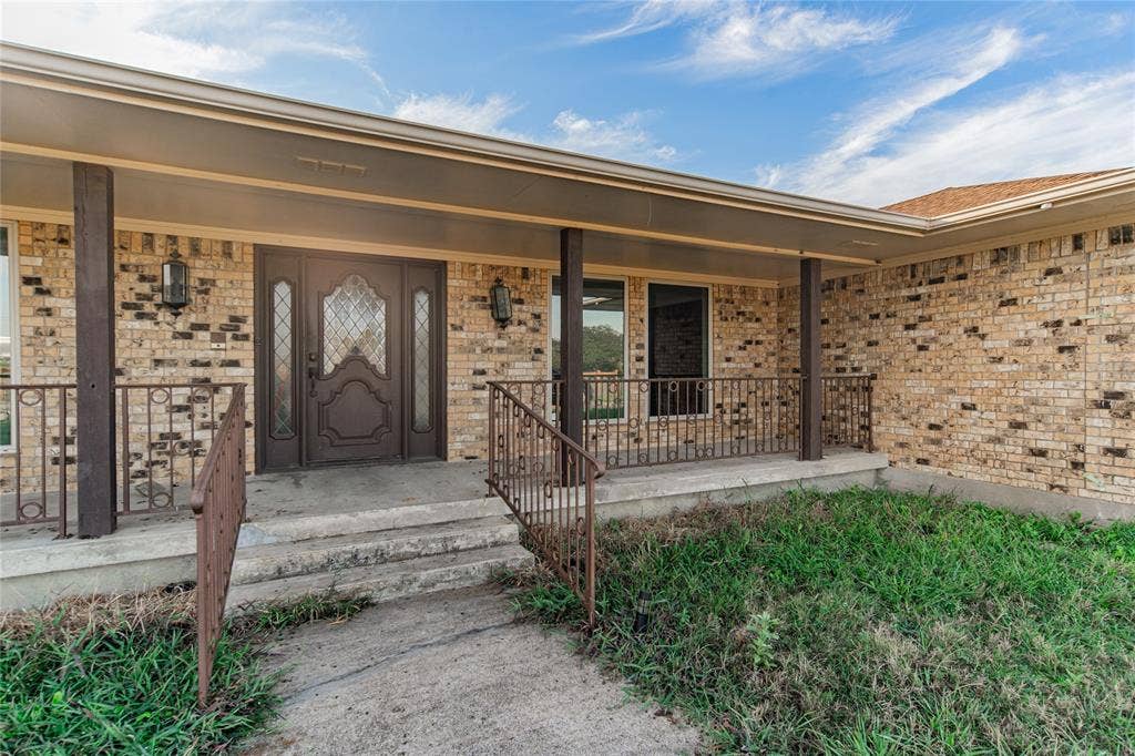 4320 Hickox Road, Rowlett, TX 75089 Brick facade with a covered entry, double entry doors, decorative glass inserts, and wrought iron railings