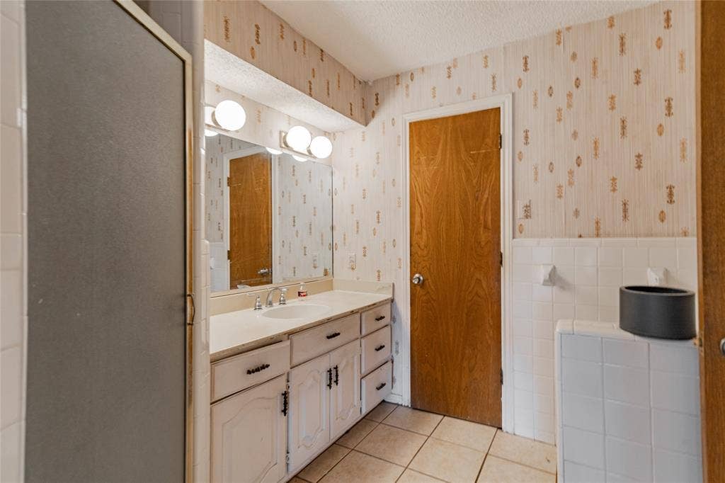 4320 Hickox Road, Rowlett, TX 75089 Single vanity with a white countertop and integrated sink, dual-door white cabinetry, and a three-bulb vanity light fixture