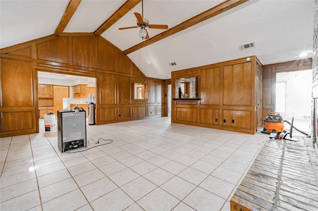 4320 Hickox Road, Rowlett, TX 75089 Vaulted ceiling with exposed wood beams, extensive wood paneling, tiled flooring, and a brick fireplace