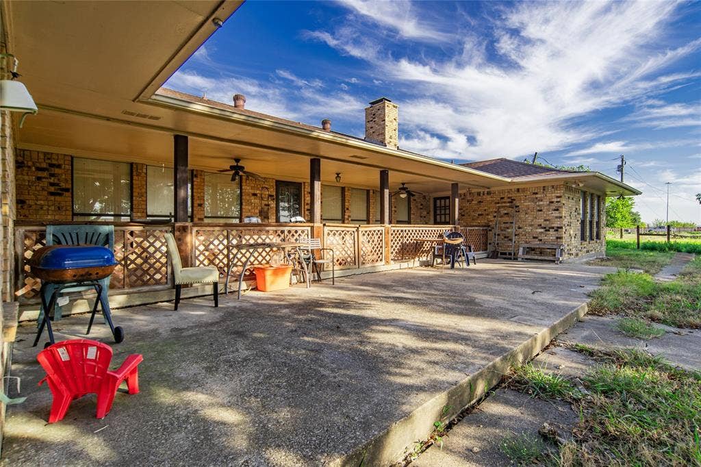 4320 Hickox Road, Rowlett, TX 75089 Expansive concrete patio with a covered porch featuring multiple support columns, a wood-lattice railing, and a ceiling fan