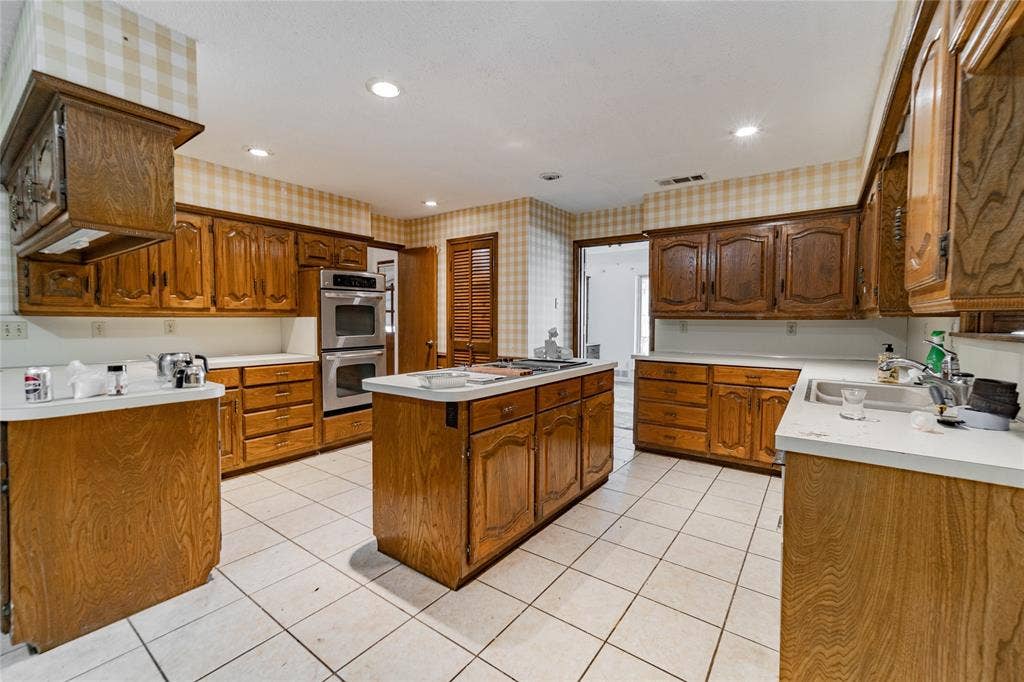 4320 Hickox Road, Rowlett, TX 75089 Kitchen featuring a central island, extensive wood cabinetry, white countertops, stainless steel double ovens, and tile flooring