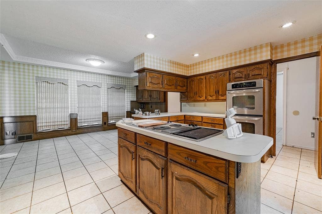 4320 Hickox Road, Rowlett, TX 75089 Kitchen featuring wood cabinetry, stainless steel double wall oven, and a center island with an integrated cooktop
