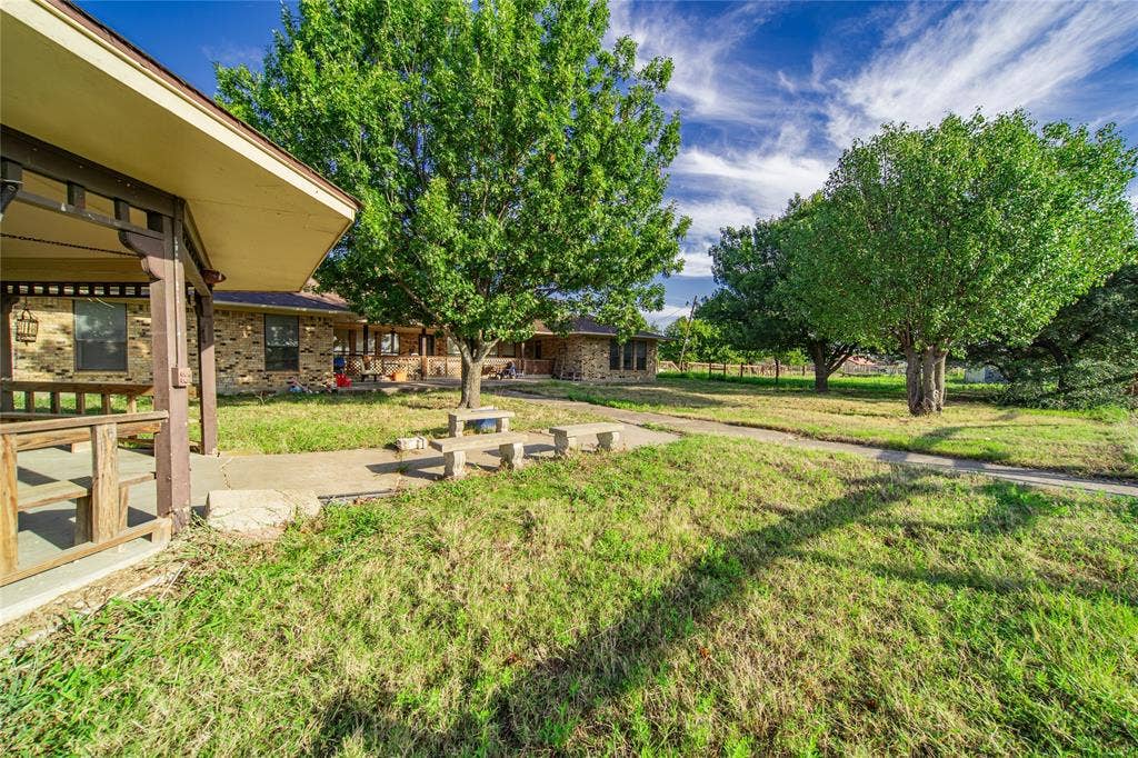 4320 Hickox Road, Rowlett, TX 75089 Expansive outdoor area featuring mature trees, a paved walkway, and a covered porch