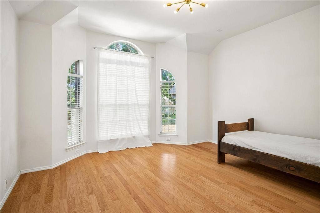 11379 Lockshire Drive, Frisco, TX 75035 Hardwood flooring, arched windows, vaulted ceiling, recessed window alcove, and contemporary ceiling light fixture