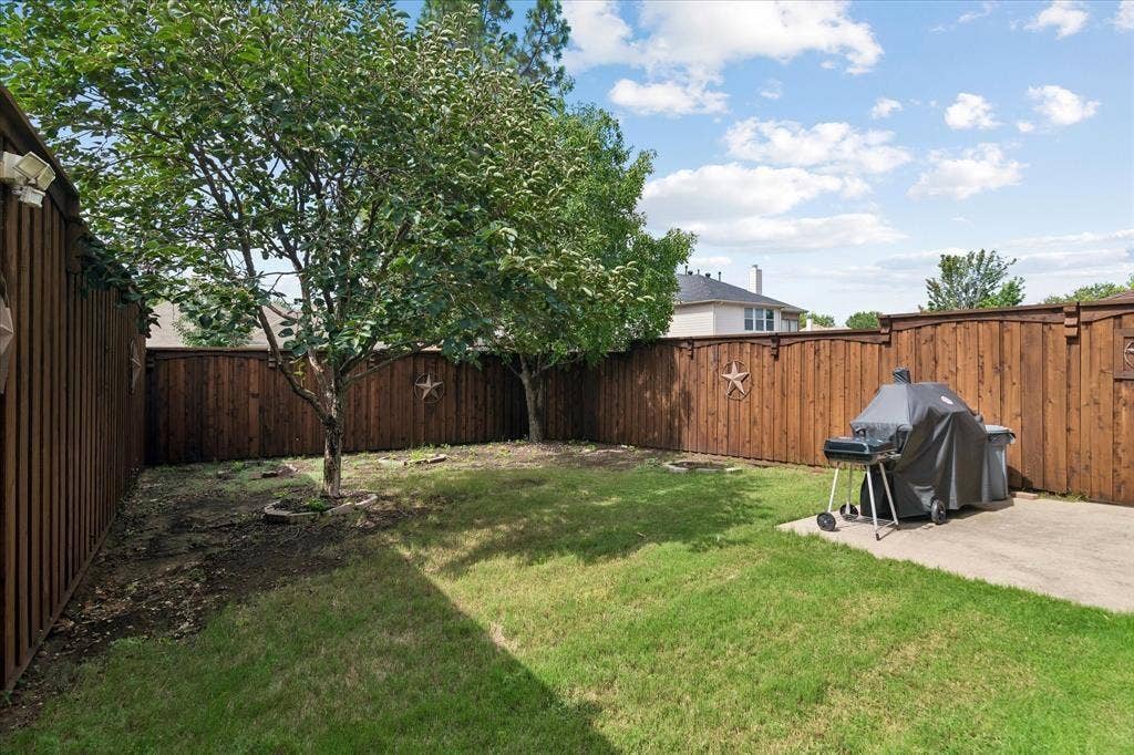 11379 Lockshire Drive, Frisco, TX 75035 Backyard featuring a wood privacy fence, concrete patio, and established trees