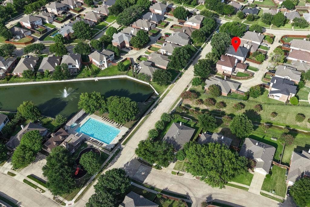 11379 Lockshire Drive, Frisco, TX 75035 Aerial perspective of a residential neighborhood featuring a central pond with fountain, a community swimming pool, and surrounding residential structures
