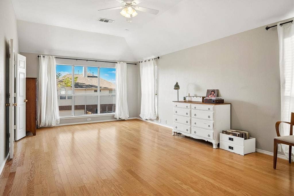 11379 Lockshire Drive, Frisco, TX 75035 Hardwood flooring, vaulted ceiling, large multi-pane window, ceiling fan, and painted interior walls