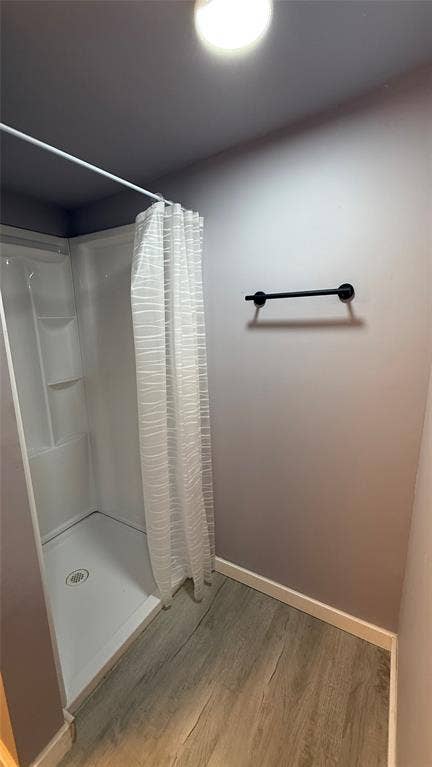 605 Biggs Terrace, Arlington, TX 76010 Shower stall with white surround, wood-finish flooring, and a matte black towel bar